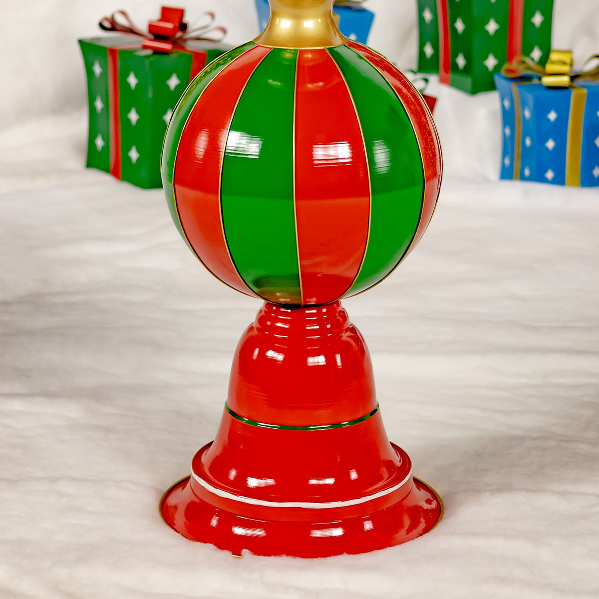 Close view of the tower’s glossy red and green striped ornament, red base, and gold trim.