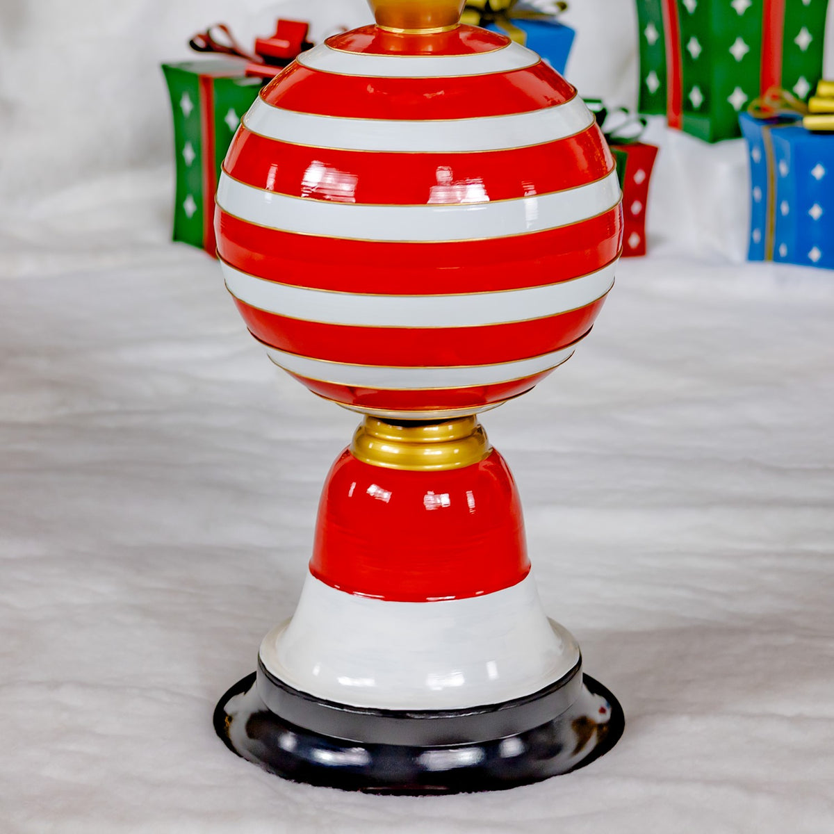 Close view of the tower’s glossy red-and-white striped ornament, gold accents, white base, and black foot.