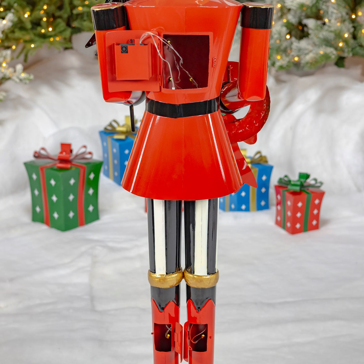 Back of the nutcracker showing its red coat, striped legs, and exposed light wiring.