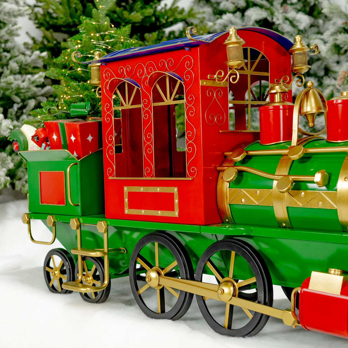 Closer side view of the train’s red carriage, green engine, gold scrollwork and large spoked wheels.