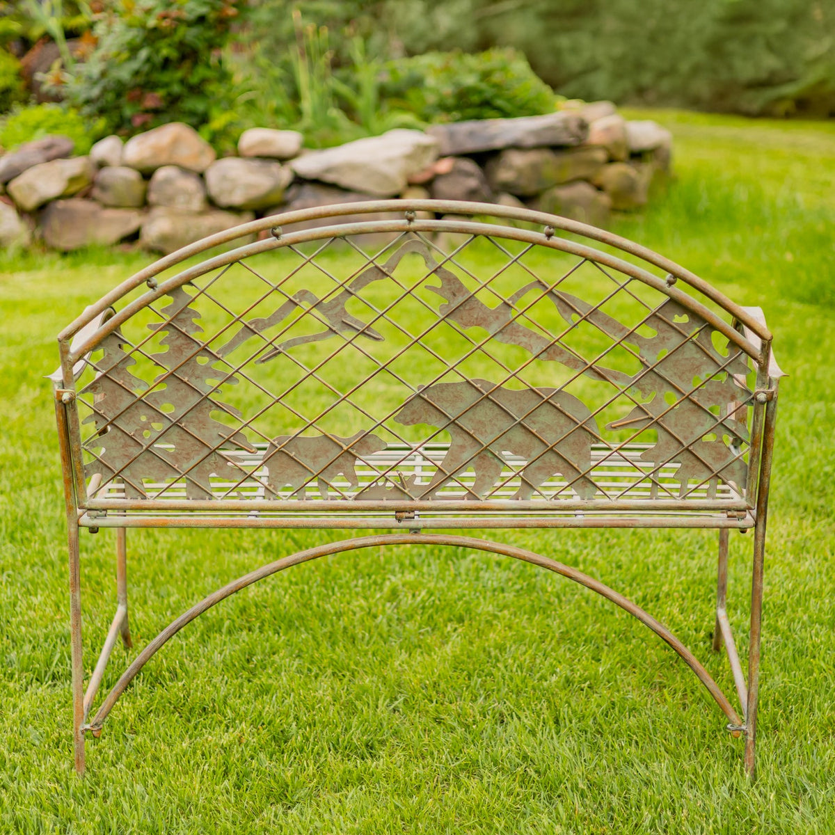 Full view of the metal bench with an arched back, mountain and wildlife silhouettes, and curved legs.