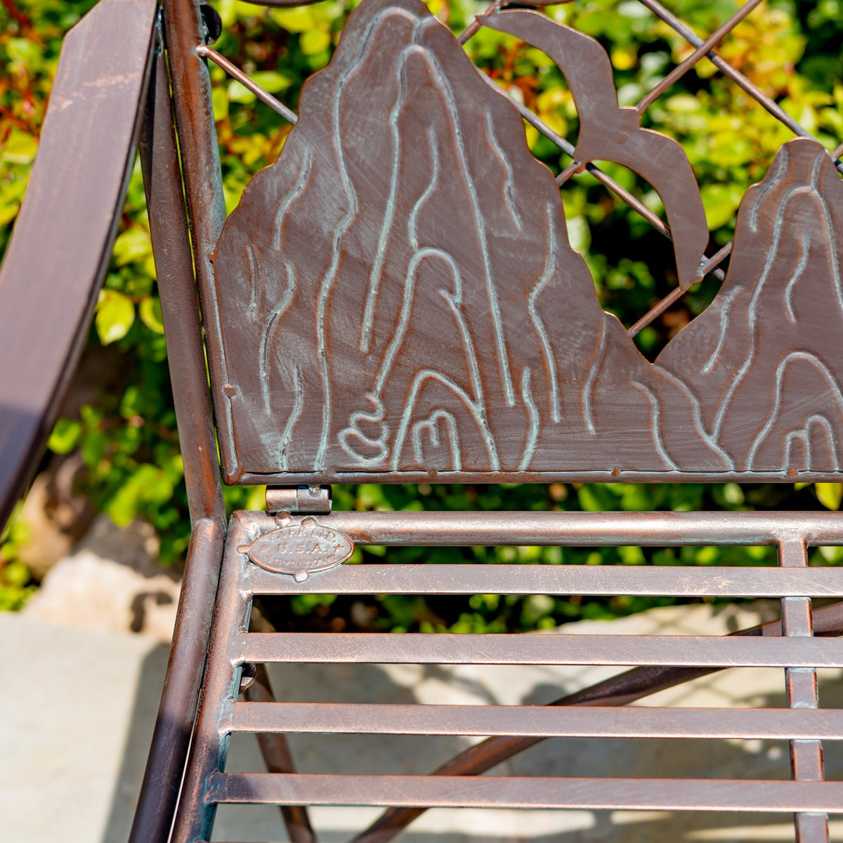 Close-up of the bench’s raised decorative backrest, metalwork, and slatted seat.