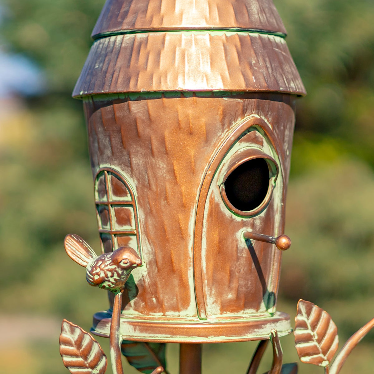 Close-up of the birdhouse entry hole, copper roof, and decorative bird