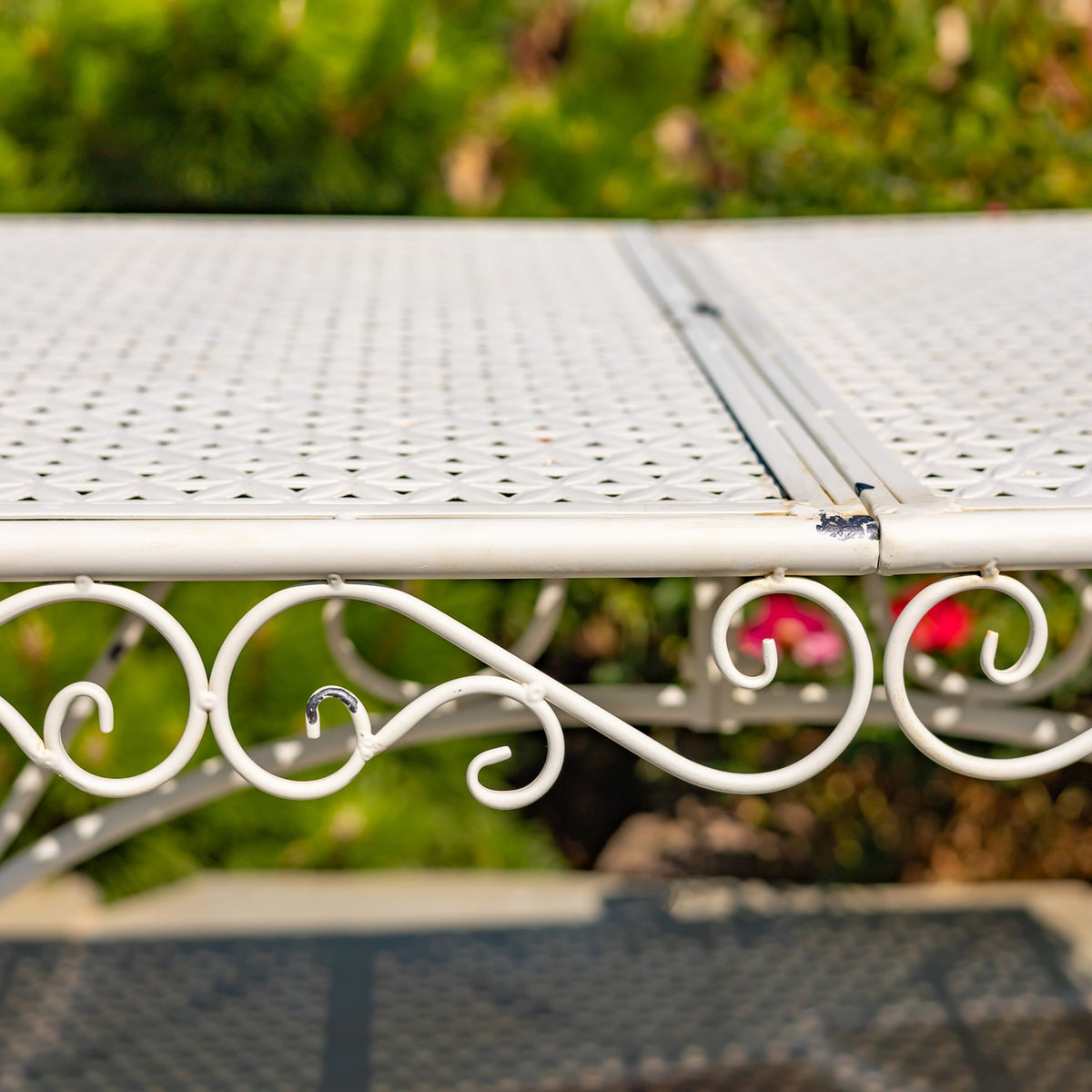 Side view of the patterned metal tabletop seam and decorative curled metalwork along the edge.