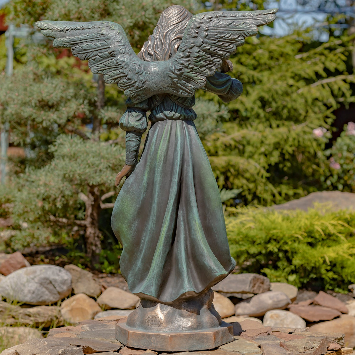 Back of the angel statue, showing outstretched wings and the folds of her flowing robe.