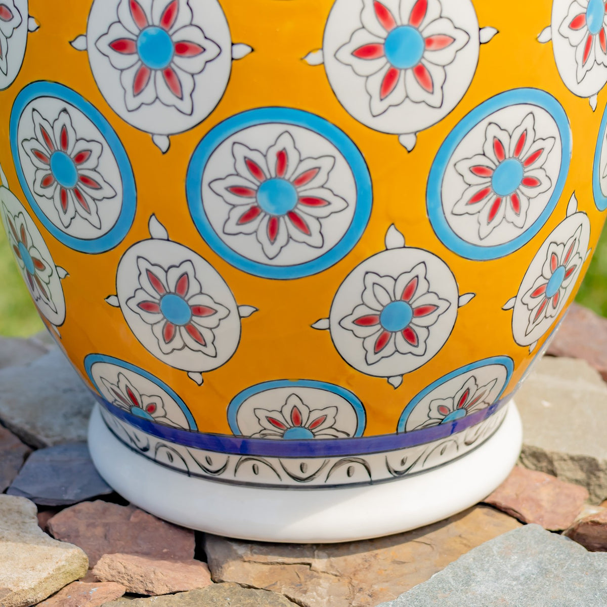 Curved yellow stool surface with repeating floral medallions above a blue band and white base.