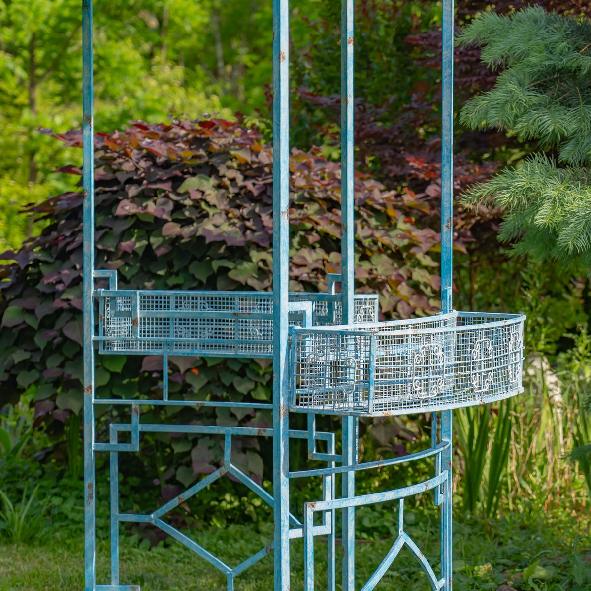 Close view of two metal planter baskets attached to the gazebo’s tall decorative frame.