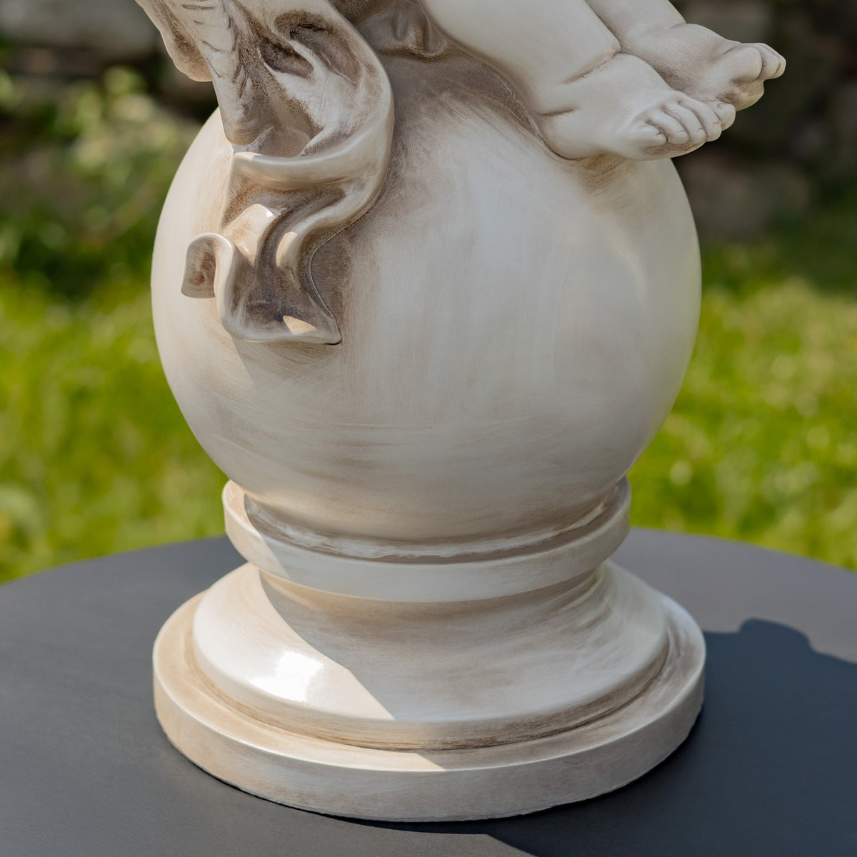 Close-up of the statue's globe pedestal and round base on a garden lawn