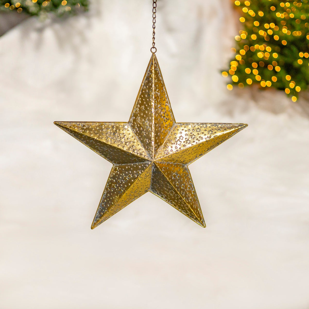 A gold star ornament with raised, textured facets hangs from a short chain.