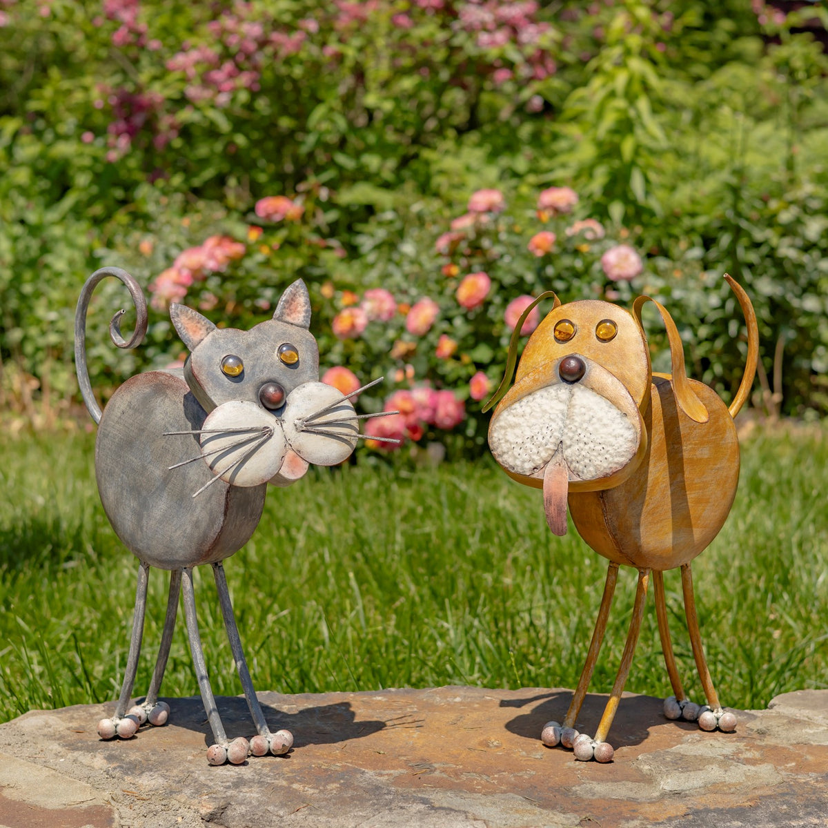 Rust-gold dog garden figure beside a gray cat figure on a stone path