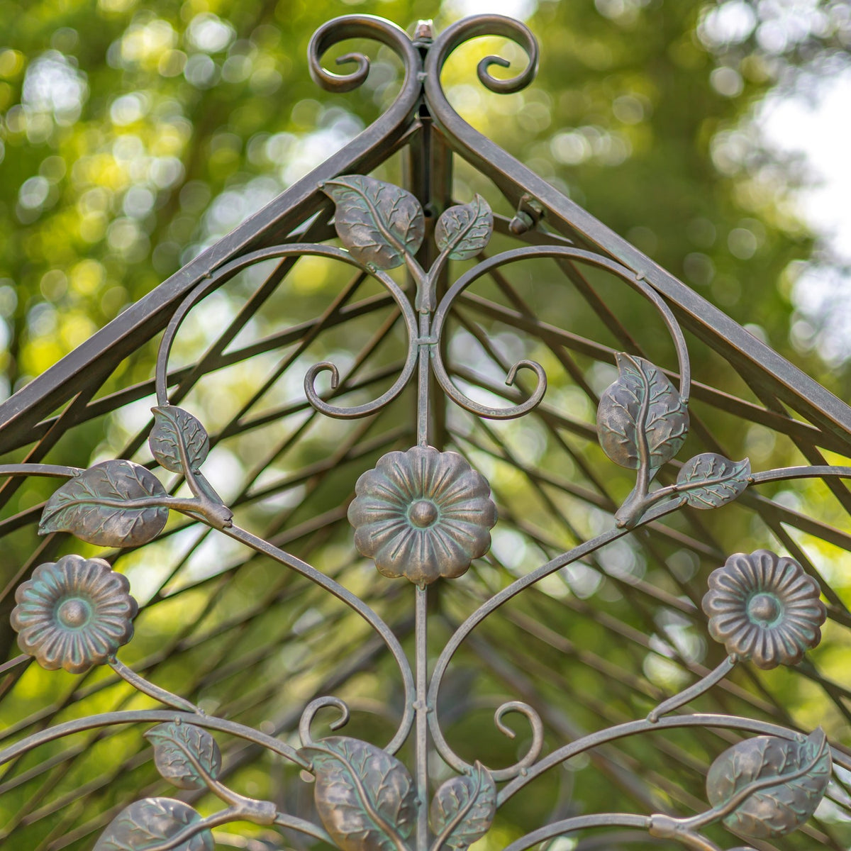 Close view of the arch peak’s iron leaves, curled stems and raised flower ornaments.