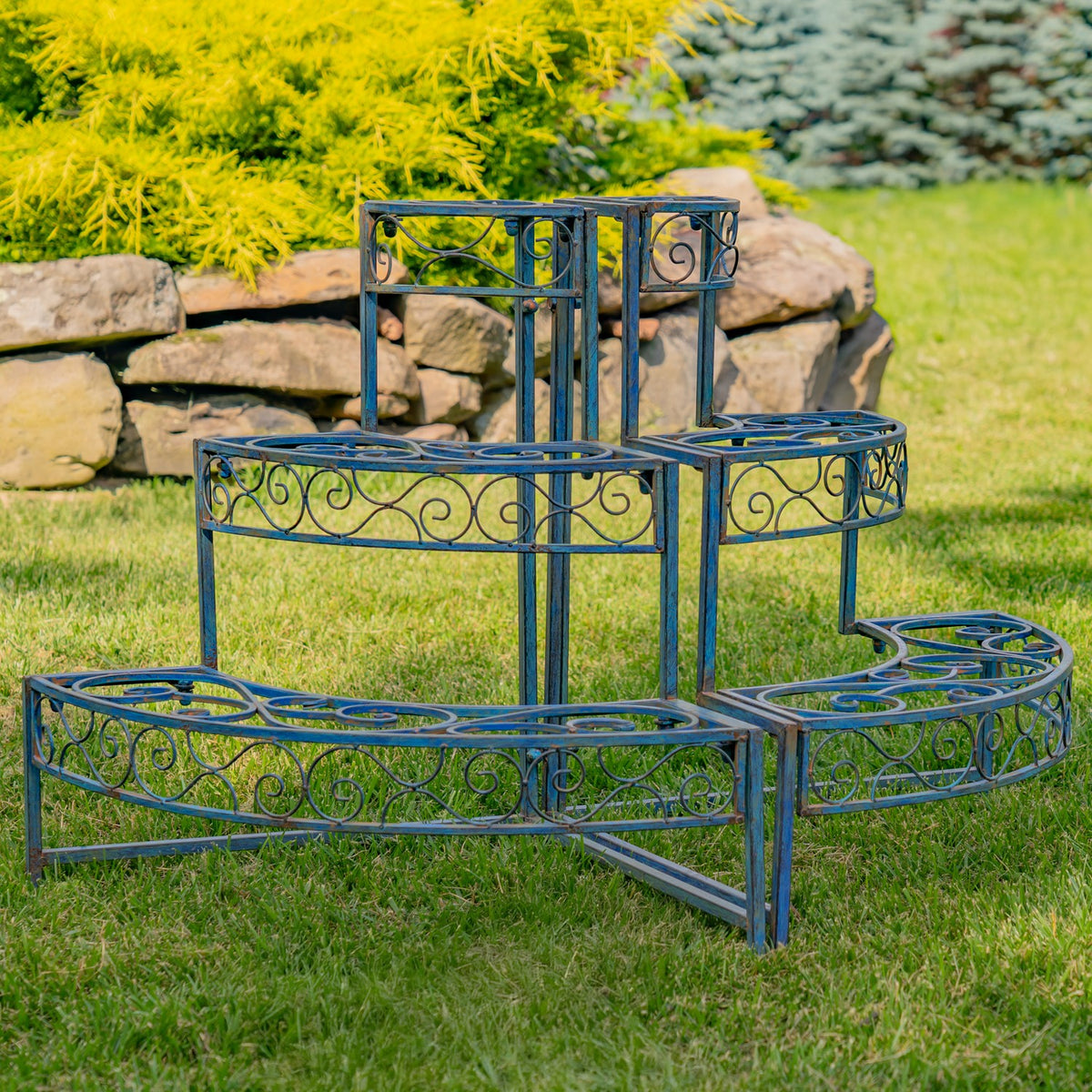 Curved tiered metal plant display with ornate scrollwork shown from the front on a lawn.