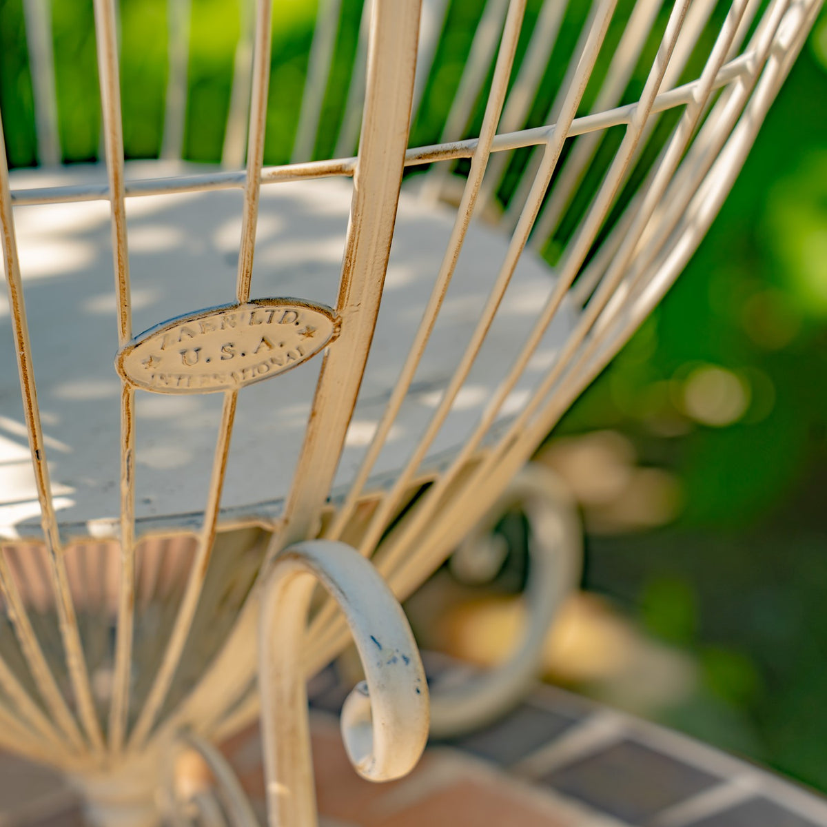 Close-up of the stand’s oval metal plaque, wire bars, and curled foot.