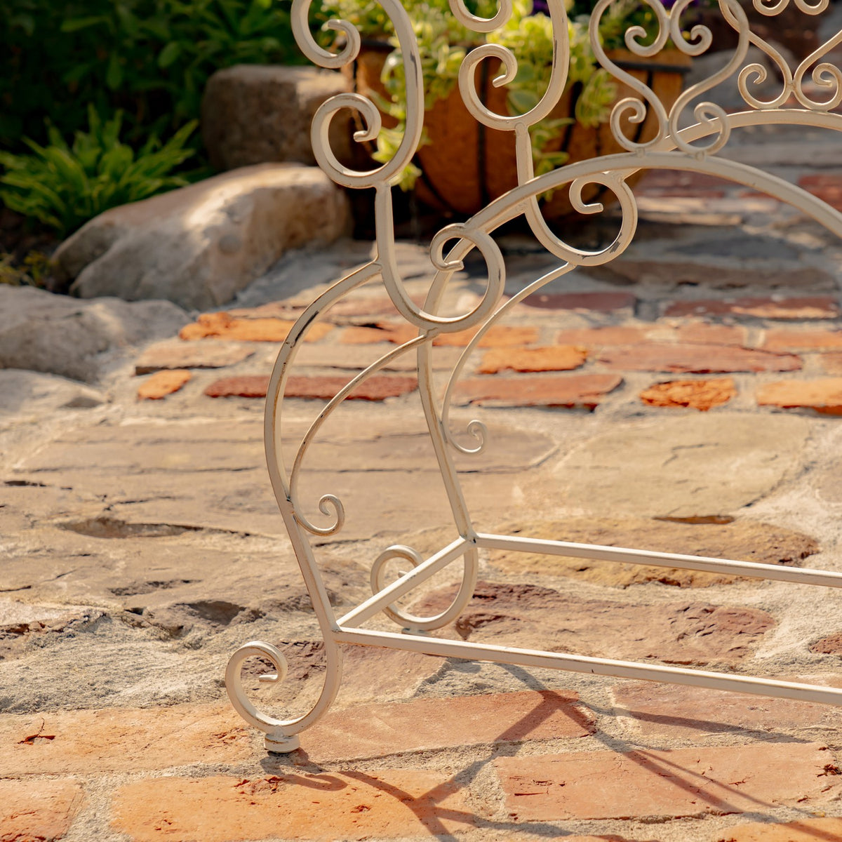 Close-up of a curled stand leg and lower crossbars resting on a stone patio.