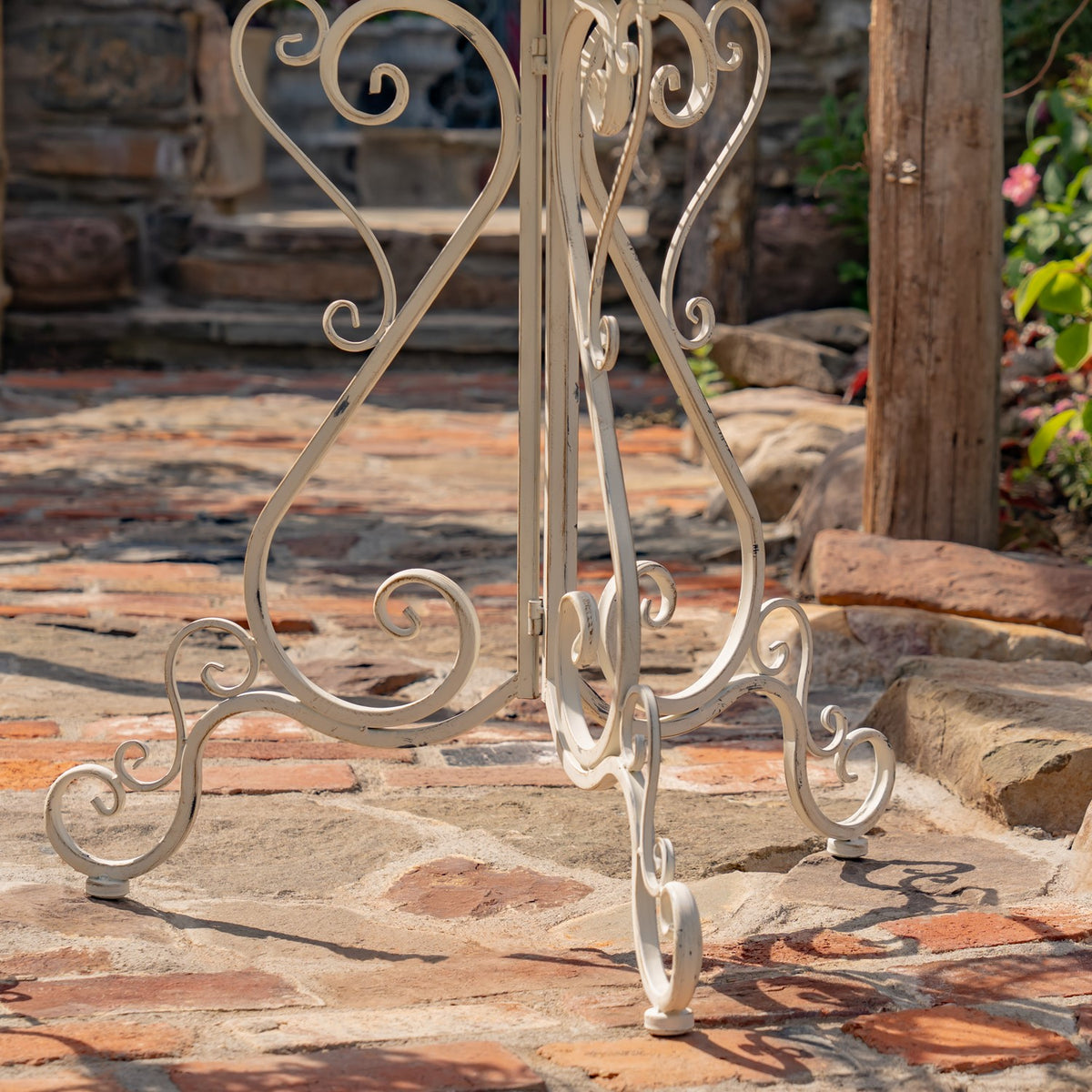 Close-up of the stand’s curved legs and curled feet on a stone patio.