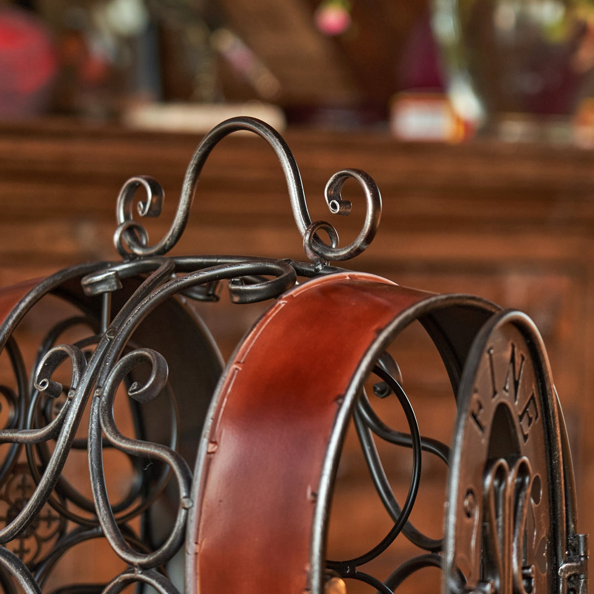 Close-up of the curved metal handle and scrollwork above the reddish-brown barrel-shaped rack.
