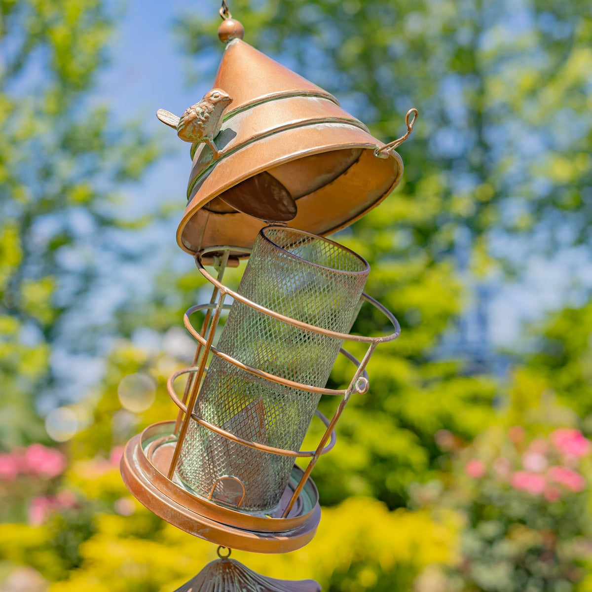 Tilted birdfeeder showing its raised roof and mesh seed cylinder
