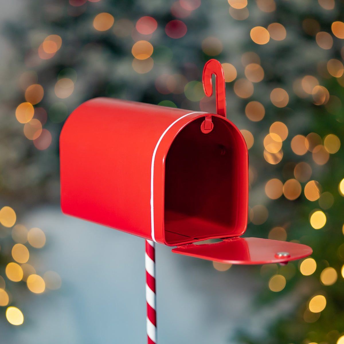 Red mailbox with its door open, showing the empty interior and striped stand post.