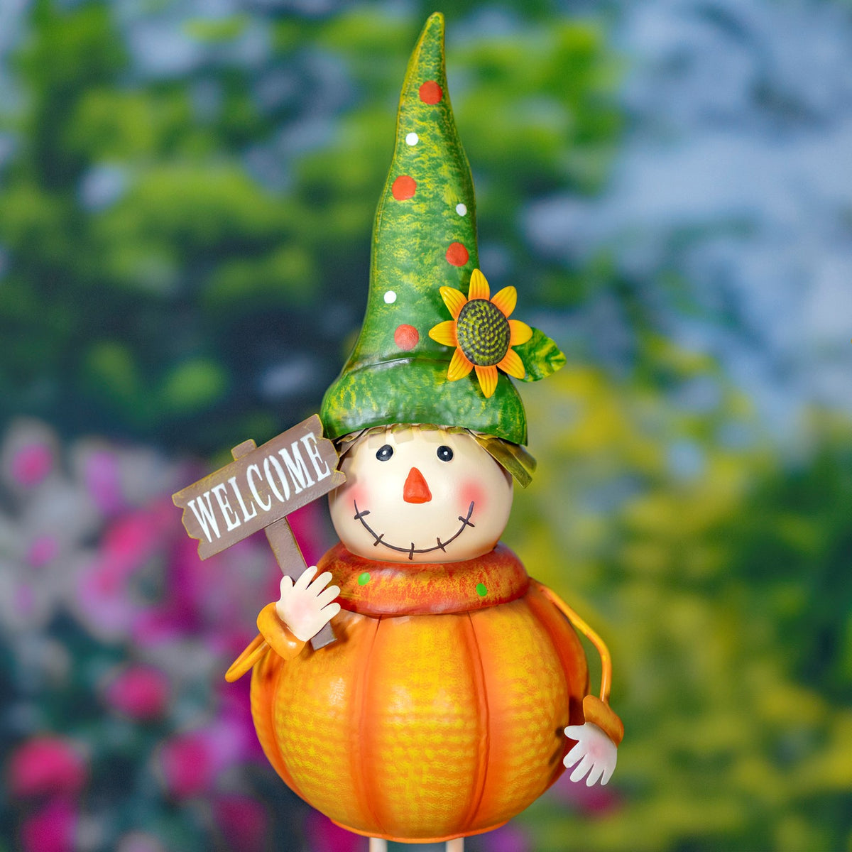 Closer view of a pumpkin scarecrow wearing a tall green sunflower hat and holding a small sign.