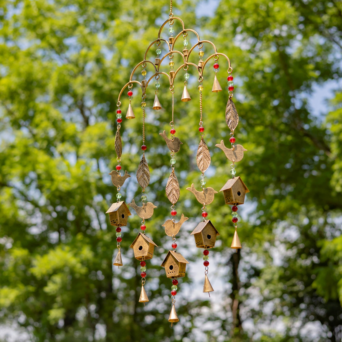 A different view of a gold-toned hanging chime with red beads, birds, leaves, and miniature birdhouses.