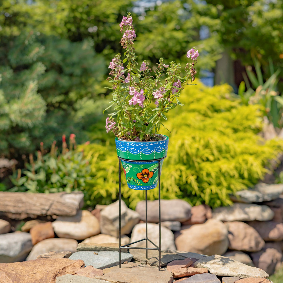 Blue hand-painted flowerpot with an orange flower motif and pink blooms, displayed on a black iron stand.