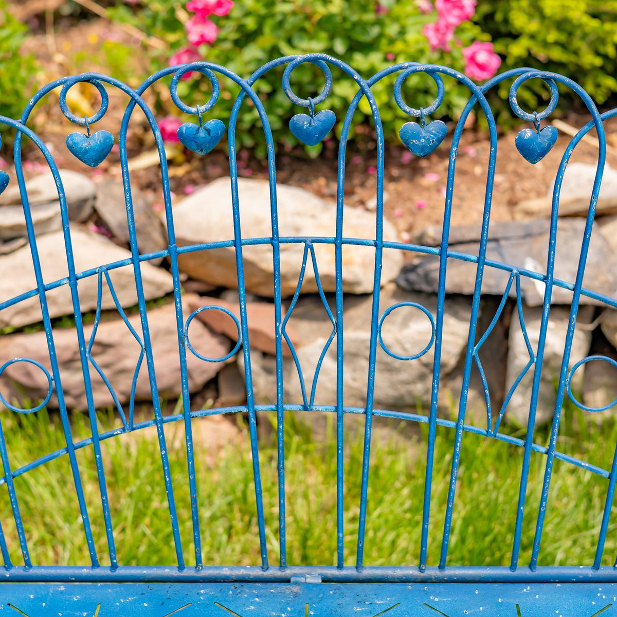 Close view of decorative blue iron scrollwork and heart accents on the bench back