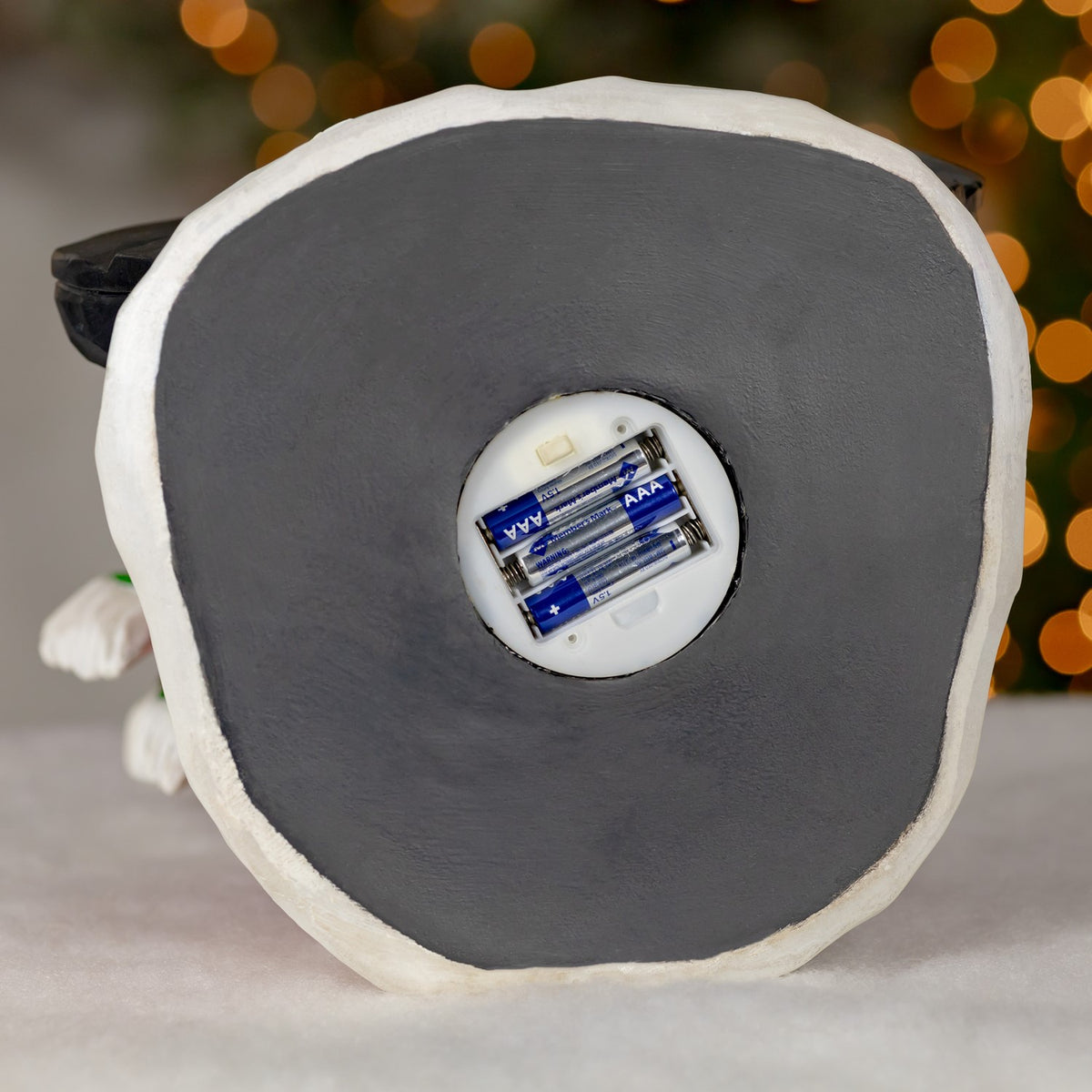 Underside of the decoration with a round battery compartment open and batteries visible.