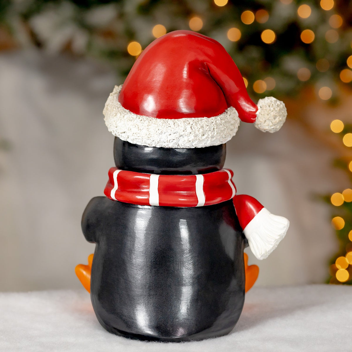 Back of the penguin decoration, showing its black body, red Santa hat and striped scarf.
