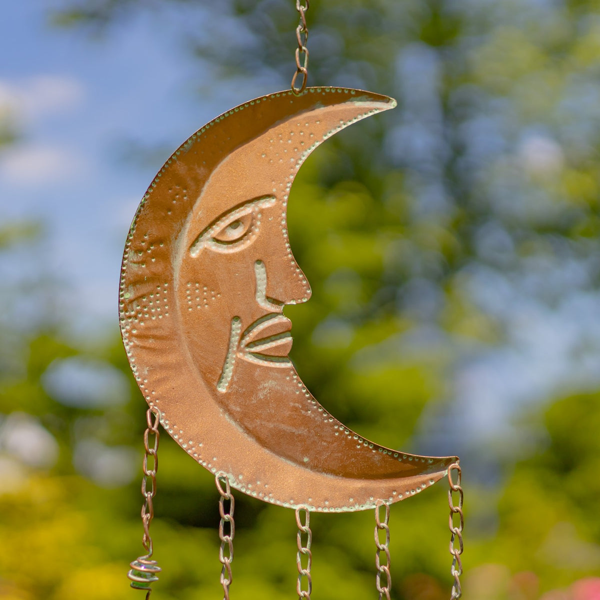 Close-up of the copper-toned crescent moon pendant, showing its engraved face and hanging chains.