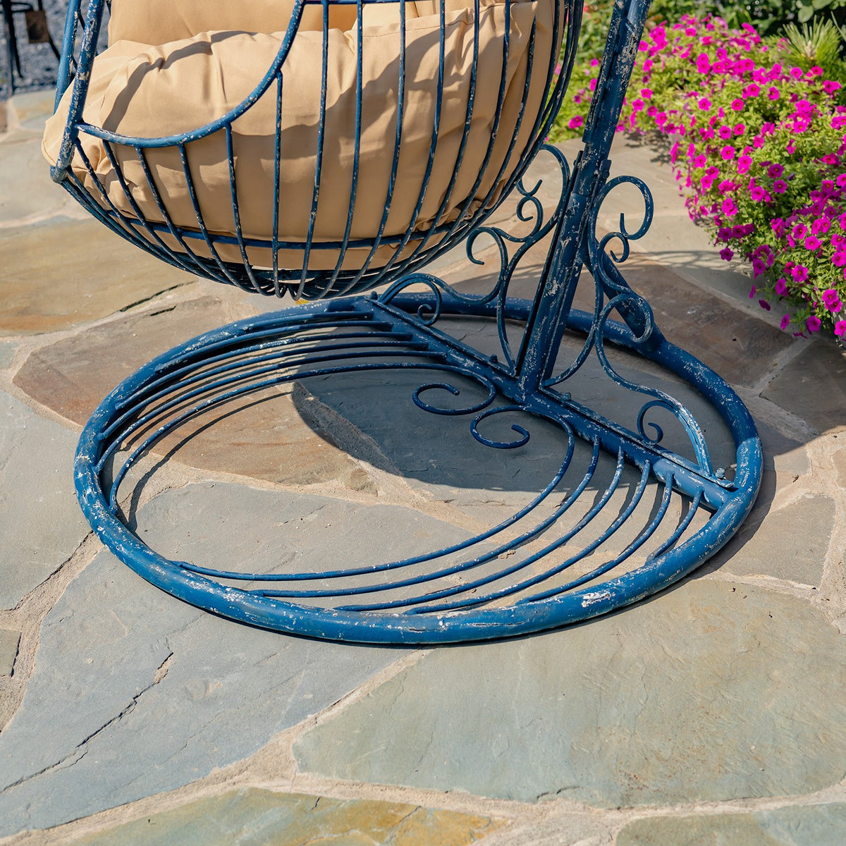 Close view of the blue chair’s circular metal base and decorative stand supports.