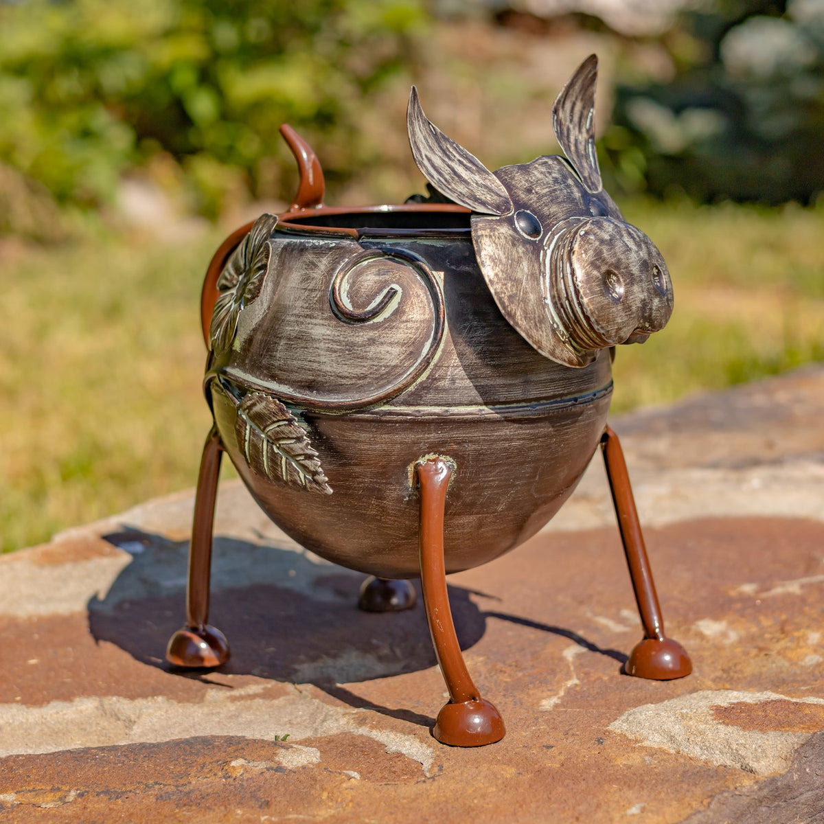 Metal animal planter shaped like a pig, showing its rounded body, curled tail, and long legs.