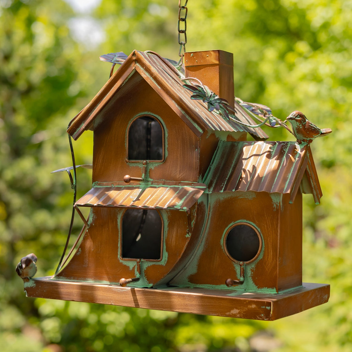 Hanging birdhouse shown from another angle, with multiple entry holes, metal roofs, and perched bird ornaments.