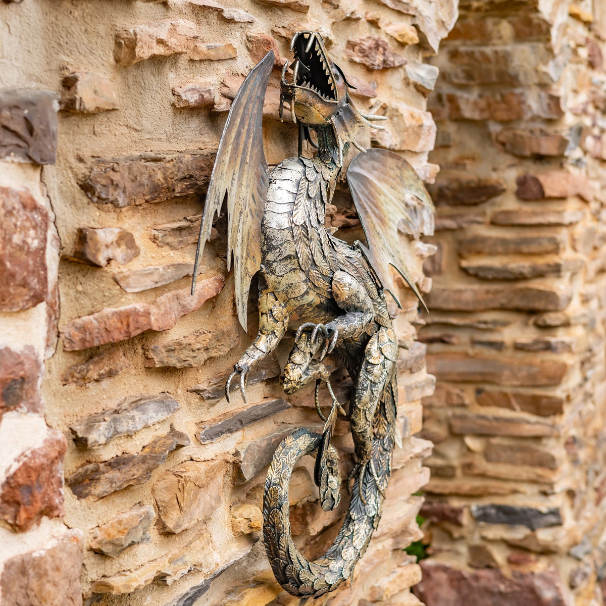 Angled view of a sculpted dragon wall decoration against a rustic stone wall.
