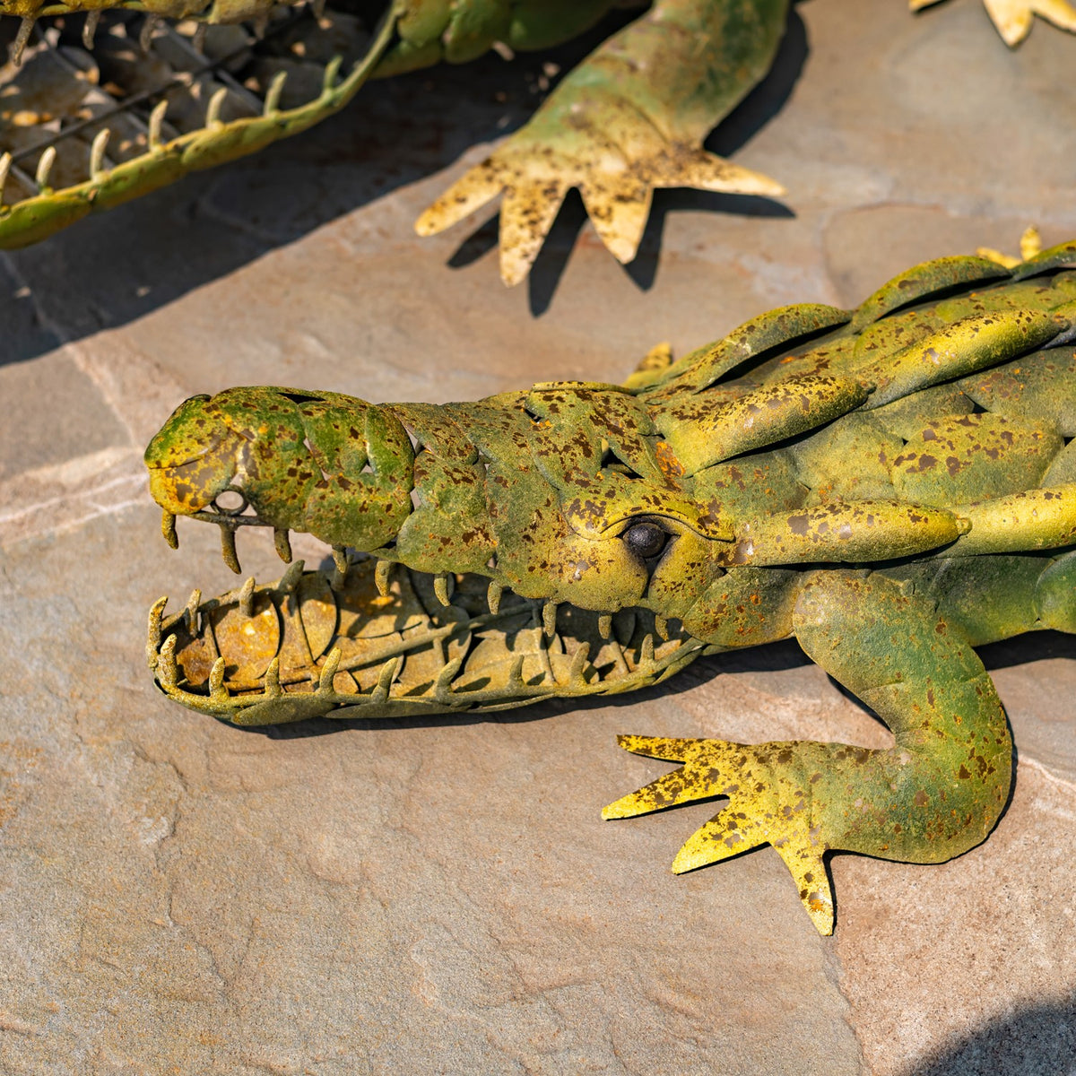 Close view of one alligator decoration’s textured head, open jaws, teeth and front leg.