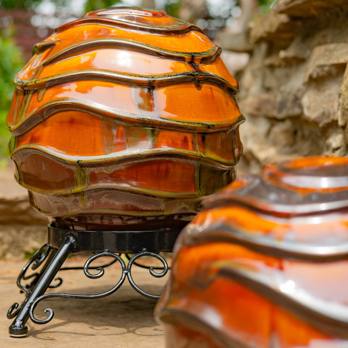 A large orange wavy globe on a curled metal stand, with another globe partly visible in the foreground.