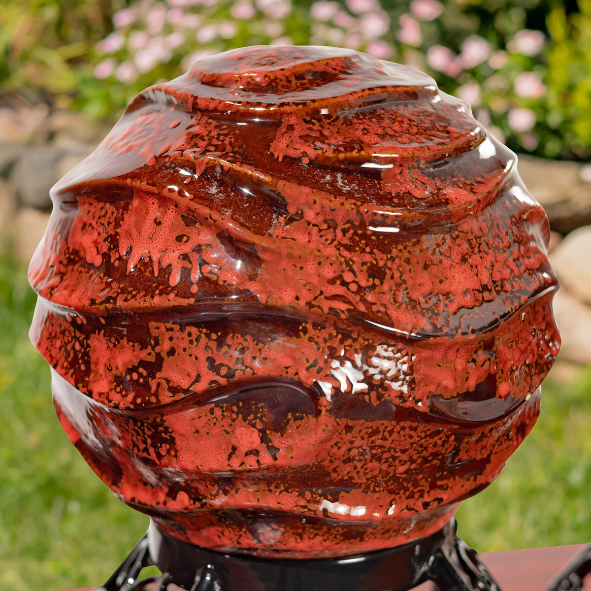 Close-up of a glossy red gazing globe with layered ridges and mottled dark accents.