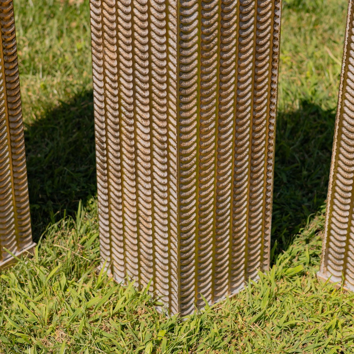 Close view of the pillars’ repeating raised pattern and square bases set in grass.