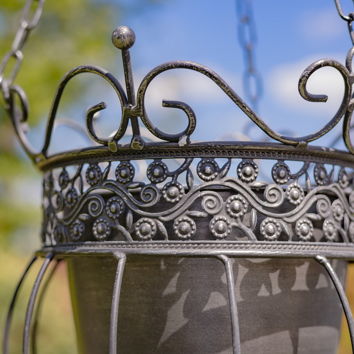 Close-up of the planter’s curled metal crown and raised floral scrollwork band.