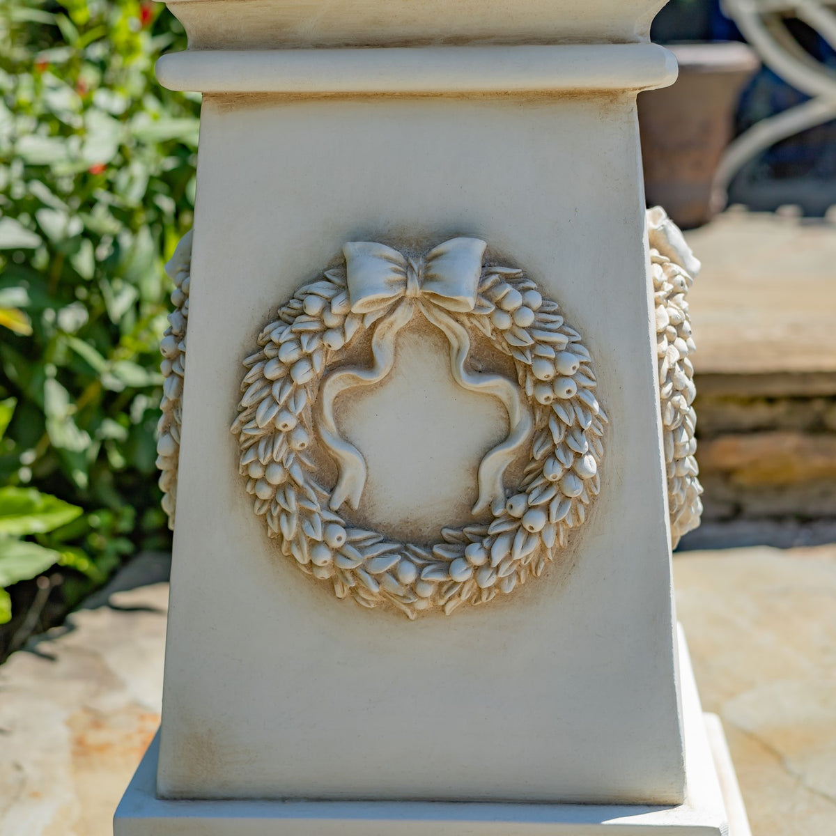 Front view of a sculpted wreath and bow relief centered on the tapered column.