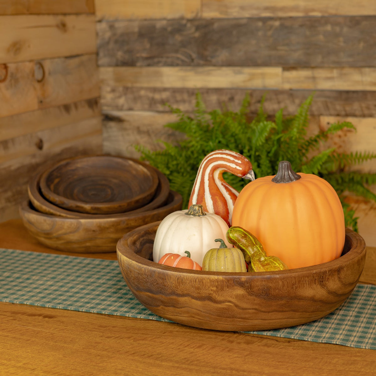 A wooden tray filled with decorative gourds, with nested trays arranged behind it.