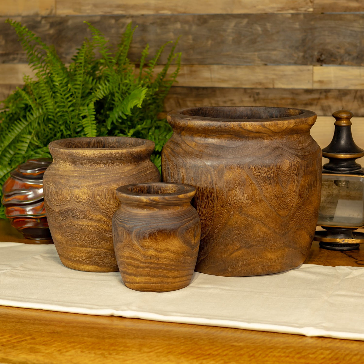 Three empty round wooden planters in graduated sizes, arranged on a light cloth.