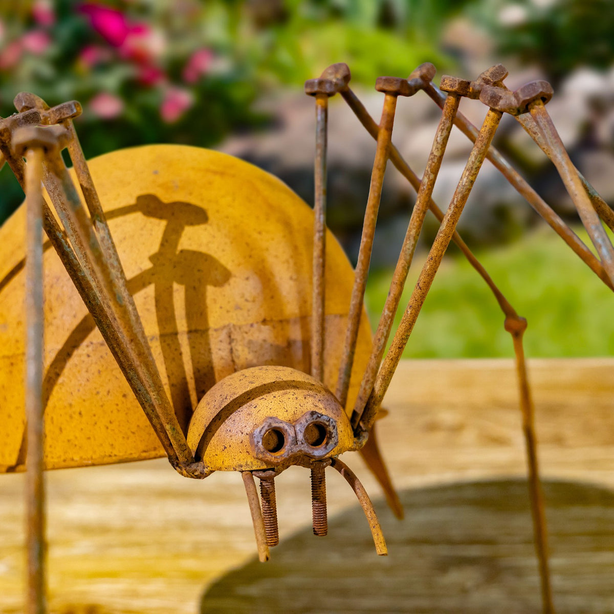 Close-up of the spider's face and rusted iron legs against greenery