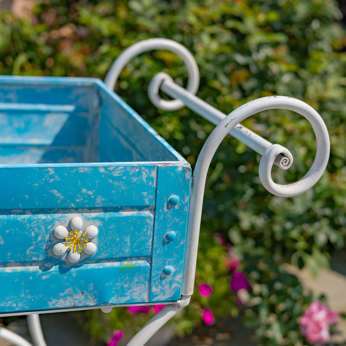 Close-up of curled white handles beside a distressed blue cart tray with a flower ornament.
