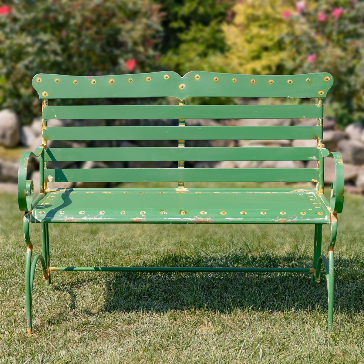 Front view of a green metal garden bench with slatted back, seat, and curved arms.