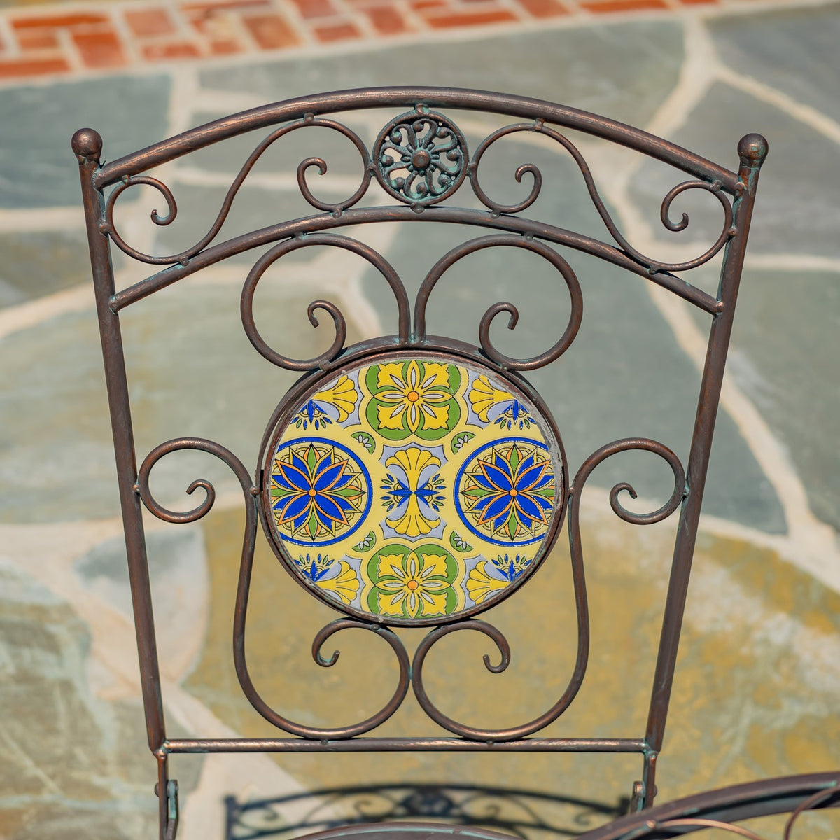 Close view of the chair’s curled metalwork and round yellow, blue, and green mosaic back panel.
