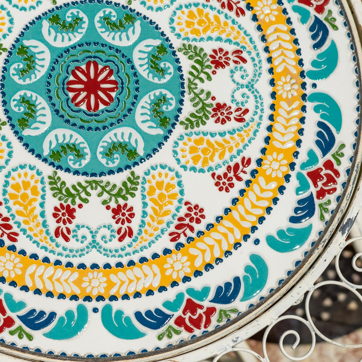 Close-up of a round mosaic surface with vivid floral patterns and a metal rim.