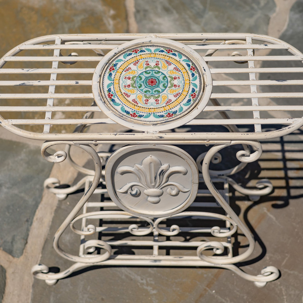 Overhead view of the stand’s round, colorful mosaic inset surrounded by cream metal slats.