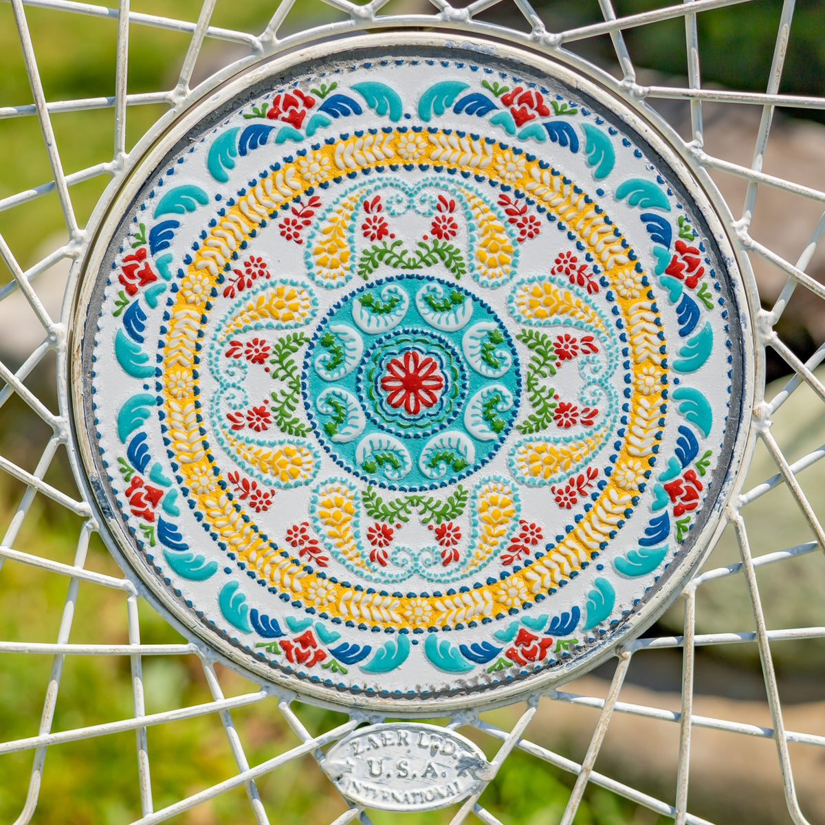 Close-up of a colorful circular floral design framed by white wirework.