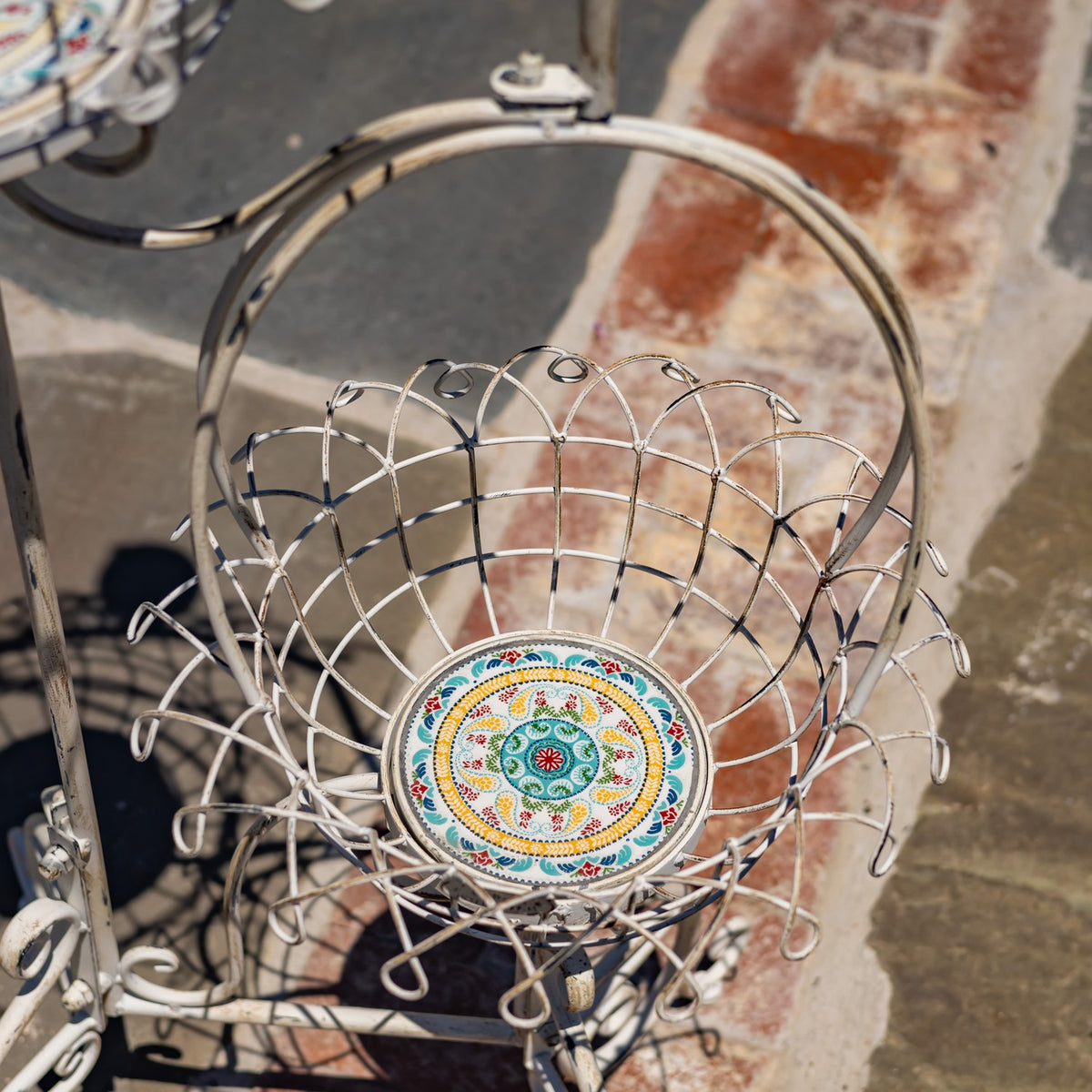 Looking down into a wire basket, showing its open lattice sides and decorative round base.