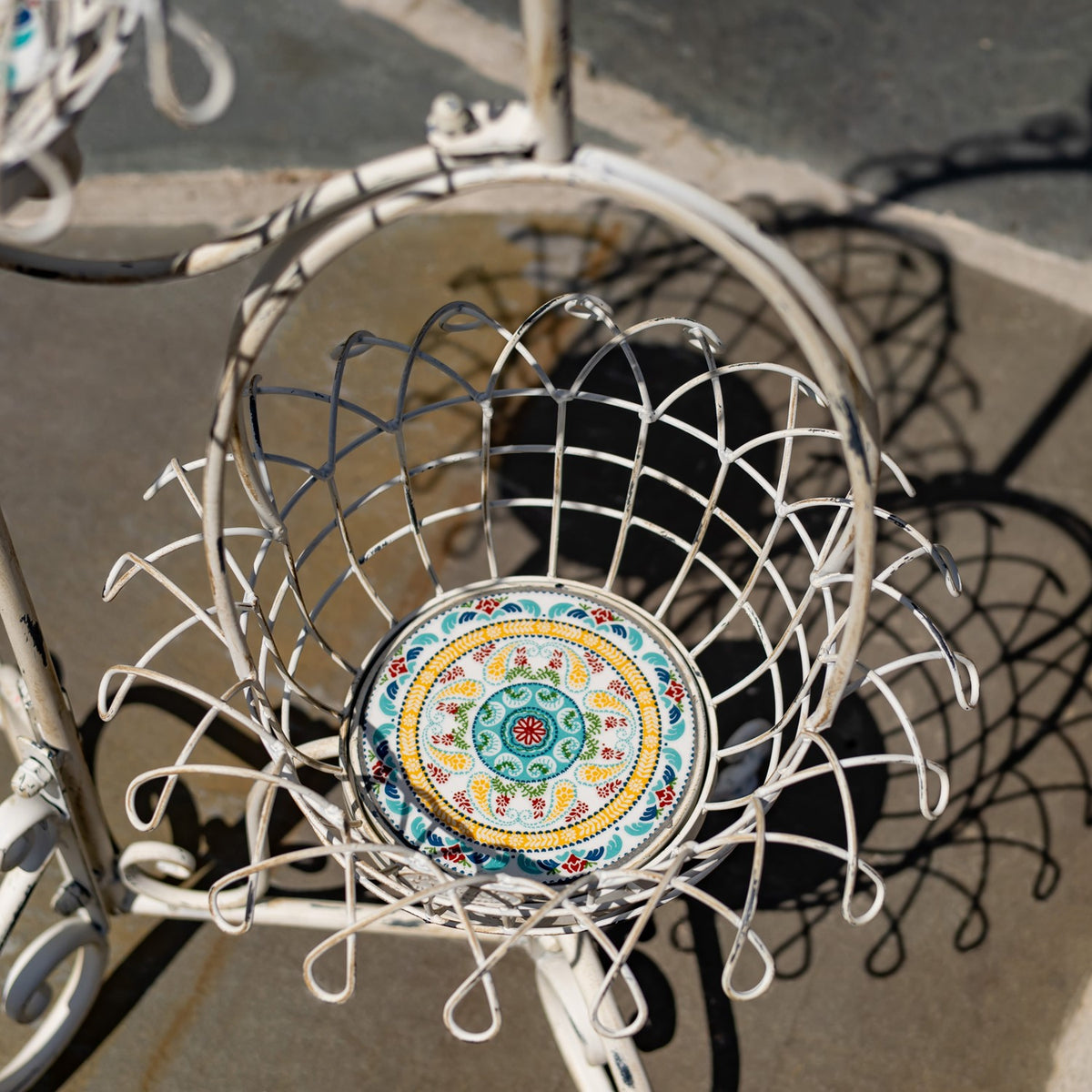 Top-down view of a white wire basket with a round, brightly patterned base.